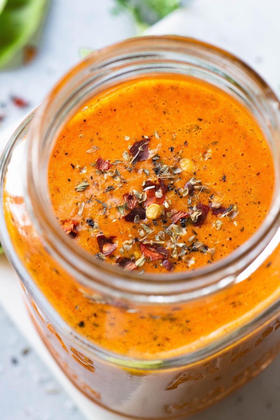 Close up view of the inside of a jar of bright orange roasted red pepper dressing