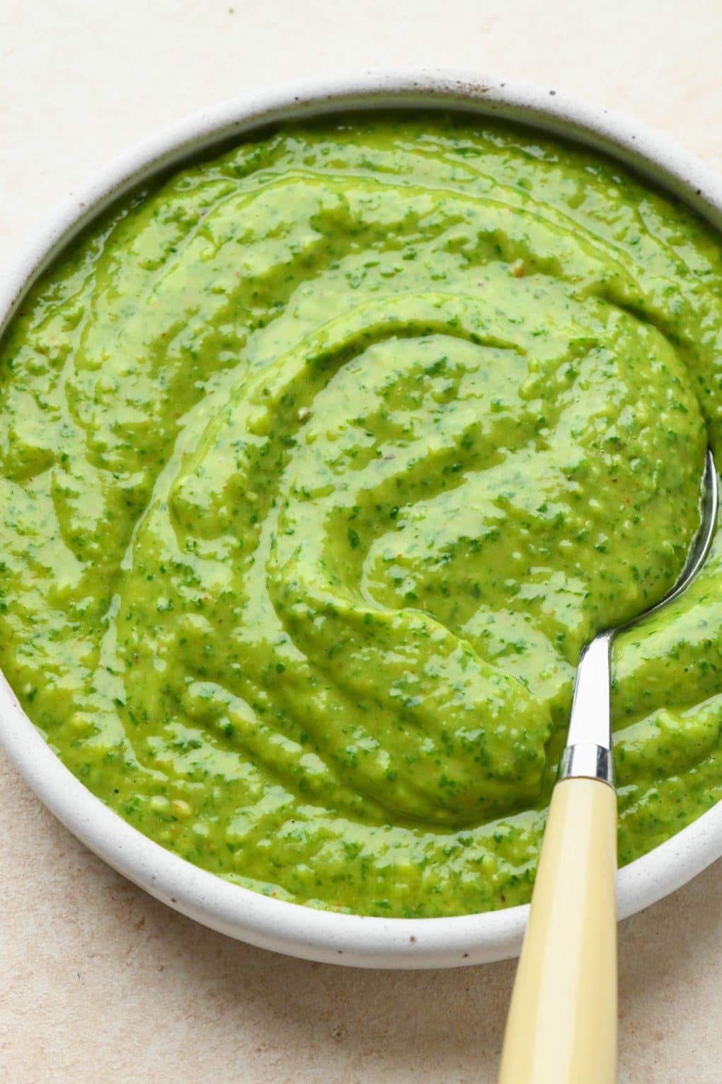 Side angle of avocado herb green sauce that shows the creamy texture of the finished sauce.