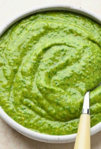 Side angle of avocado herb green sauce that shows the creamy texture of the finished sauce.