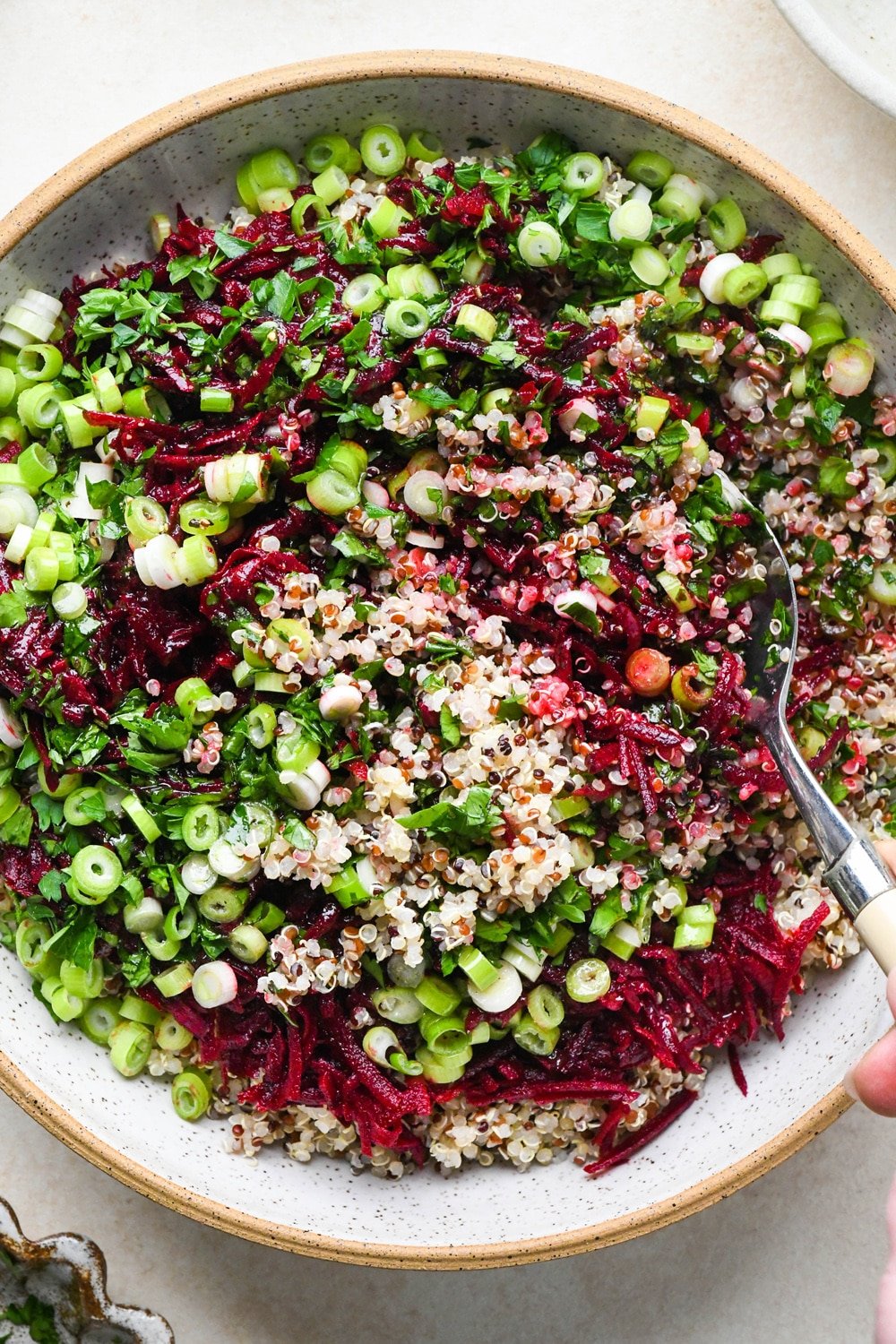How to make quinoa and fresh beet salad: A large spoon mixing together quinoa salad.