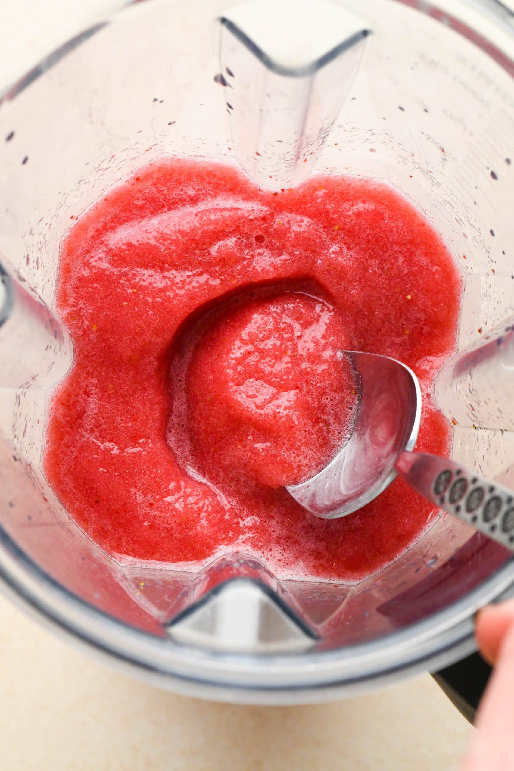 How to make Strawberry Hibiscus Slushies: Spoon dipping into slushy in blender container to show frozen texture.