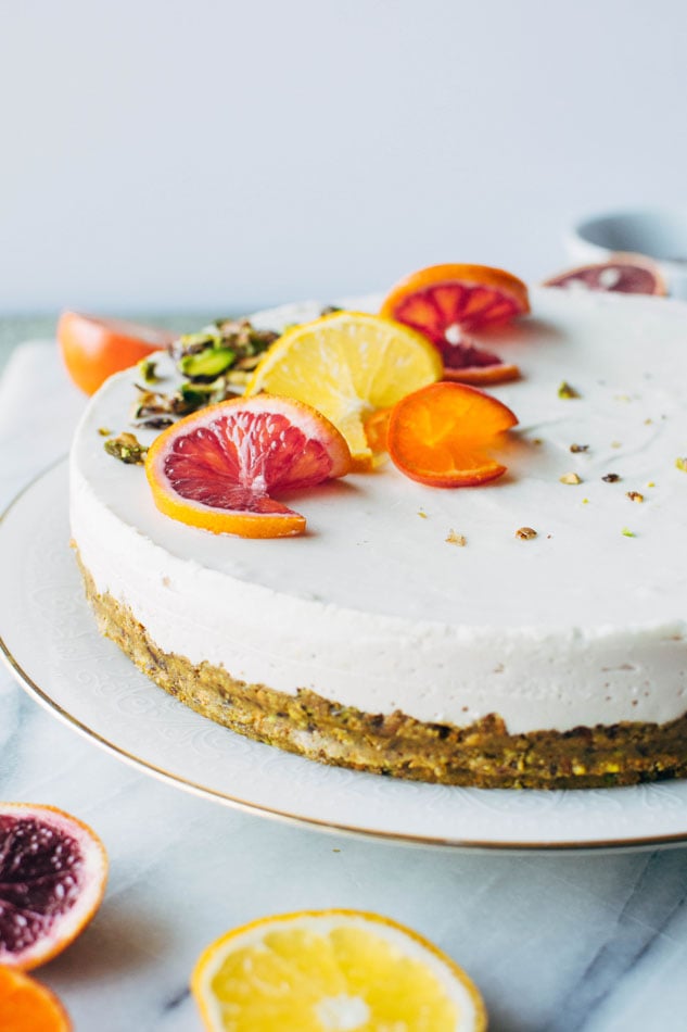 Blood orange and cardamom pistachio no bake greek yogurt cheesecake! A delightful + healthy gluten free dessert that will satisfy your cheesecake loving sweet tooth. Made with greek yogurt, coconut, blood oranges, vanilla, a date-sweetened pistachio crust and topped with fresh citrus and cardamom candied pistachios.