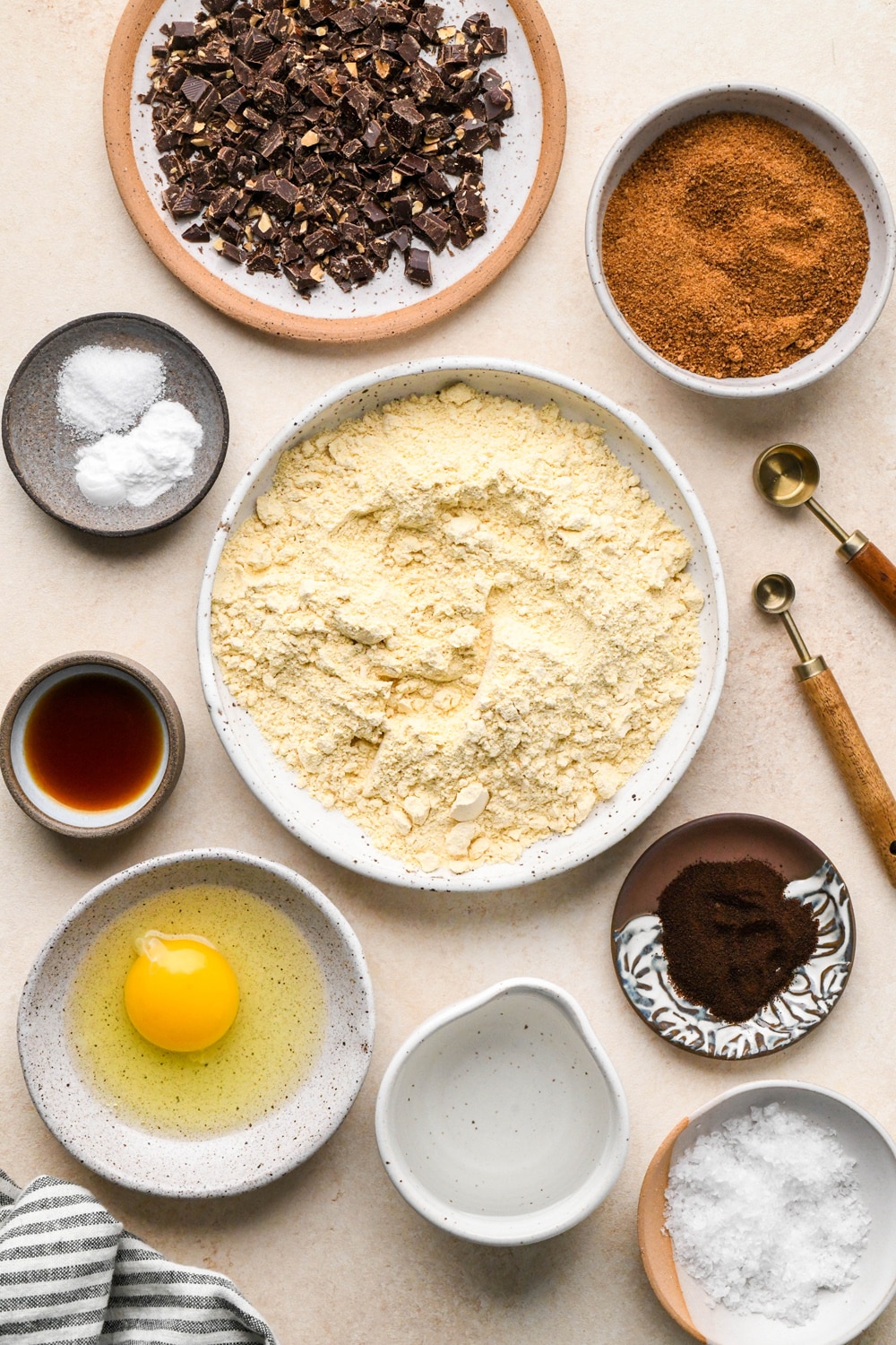 Ingredients for chocolate espresso chickpea flour cookies in various ceramics on a light cream colored background.