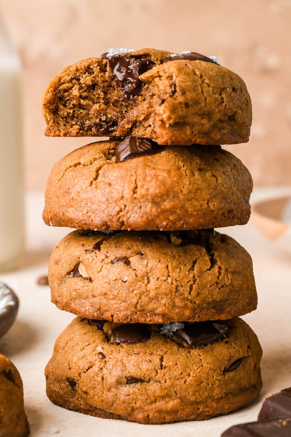 A tall stack of four dark chocolate chickpea flour cookies. The top cookie has a bite taken out of it to show the interior texture.