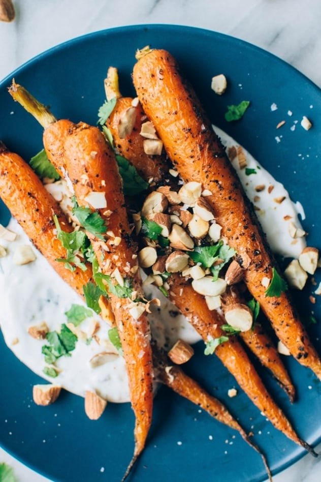 Black pepper roasted carrots with savory cilantro yogurt and roasted almonds are super easy and flavor packed to the max! The carrots are seasoned with black pepper, a little bit of paprika, and paired with a bright + savory cilantro yogurt sauce - the perfect combo! Topped with some roasted almonds to add some texture and crunch for the win!