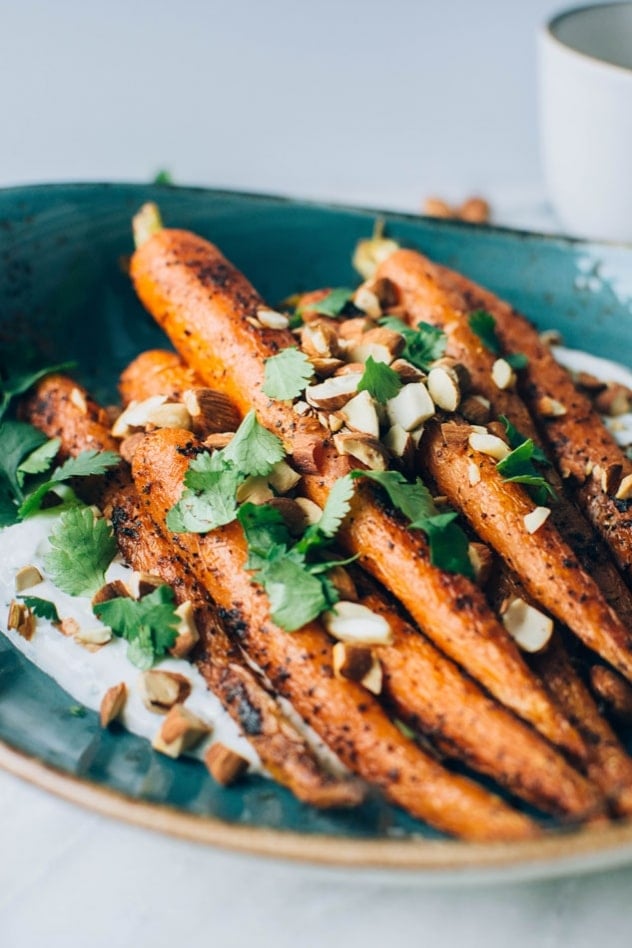 Black pepper roasted carrots with savory cilantro yogurt and roasted almonds are super easy and flavor packed to the max! The carrots are seasoned with black pepper, a little bit of paprika, and paired with a bright + savory cilantro yogurt sauce - the perfect combo! Topped with some roasted almonds to add some texture and crunch for the win!