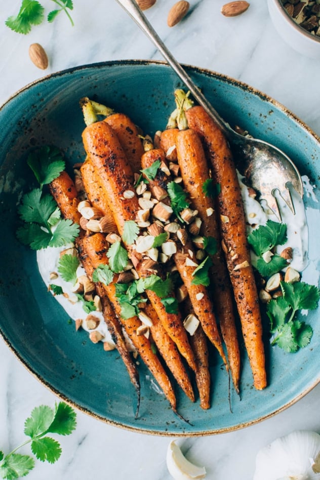 Black pepper roasted carrots with savory cilantro yogurt and roasted almonds are super easy and flavor packed to the max! The carrots are seasoned with black pepper, a little bit of paprika, and paired with a bright + savory cilantro yogurt sauce - the perfect combo! Topped with some roasted almonds to add some texture and crunch for the win!