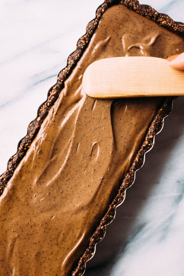 Spreading the filling for salted mocha hazelnut tart with Rawmio chocolate - an incredibly decadent and satisfying vegan and paleo dessert! No bake, made with nutrient dense ingredients, and sprinkled with sea salt like every great chocolate dessert should be.