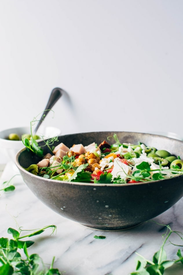 Loaded greek salad bowl with crispy chickpeas and creamy jalepeño dressing is satisfying, healthy and easy to make! Packed with crisp greens, loads of veggies, buttery casteltravano olives, crispy chickpeas and feta cheese it's a salad lovers DREAM!