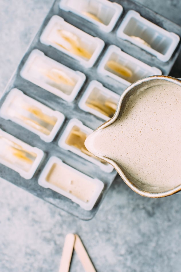 Pouring batter into popsicle molds for salted banana date popsicles. An amazing paleo and vegan frozen treat that are made with a few simple and healthy ingredients!