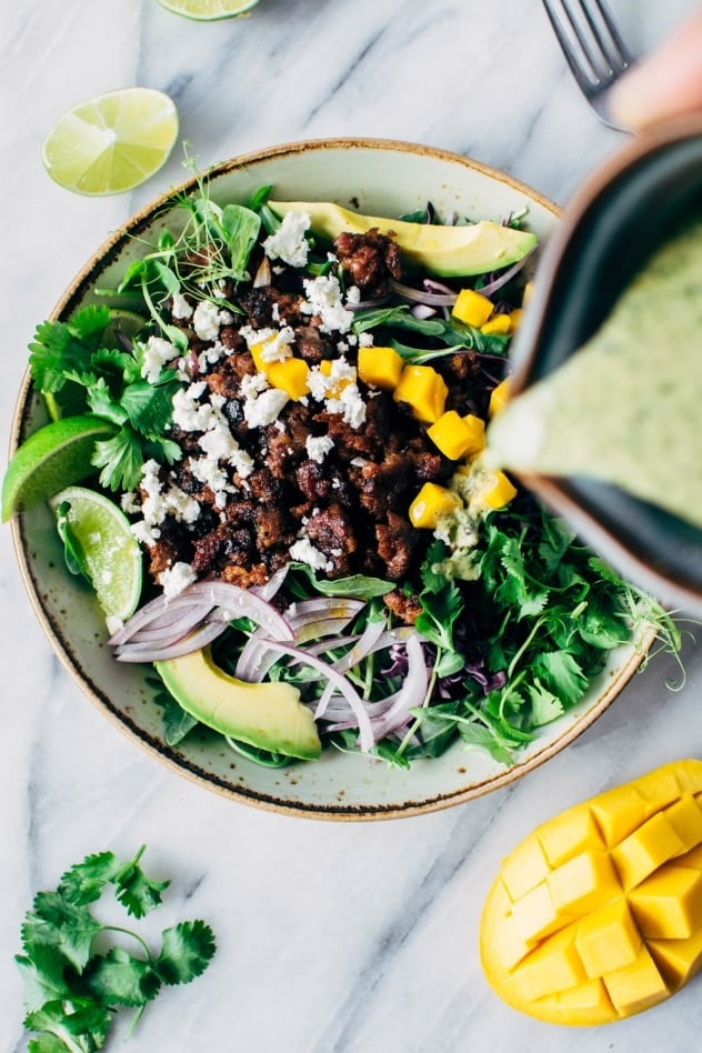 Mango chorizo taco salad bowls with green sauce! Spicy crumbled chorizo layered over salad greens with a rainbow of veggies and all your favorite toppings.