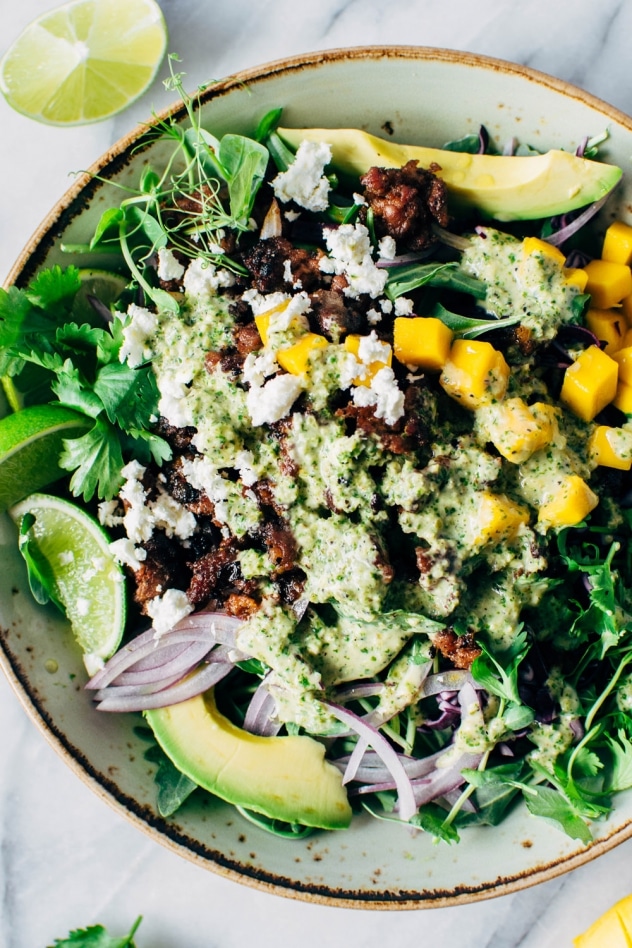 Mango chorizo taco salad bowls with green sauce! Spicy crumbled chorizo layered over salad greens with a rainbow of veggies and all your favorite toppings.