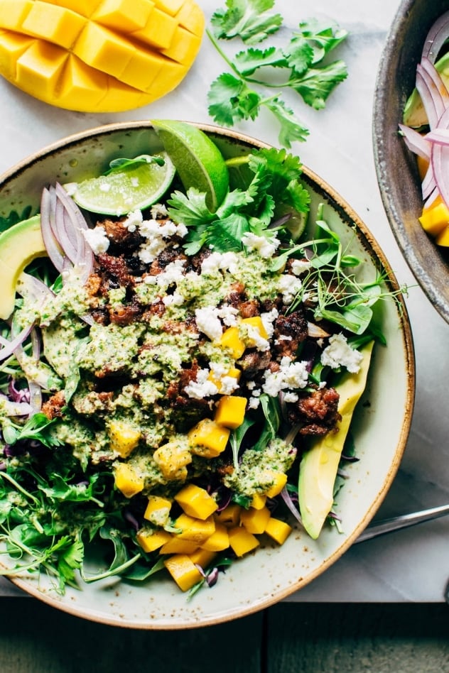 Mango chorizo taco salad bowls with green sauce! Spicy crumbled chorizo layered over salad greens with a rainbow of veggies and all your favorite toppings.