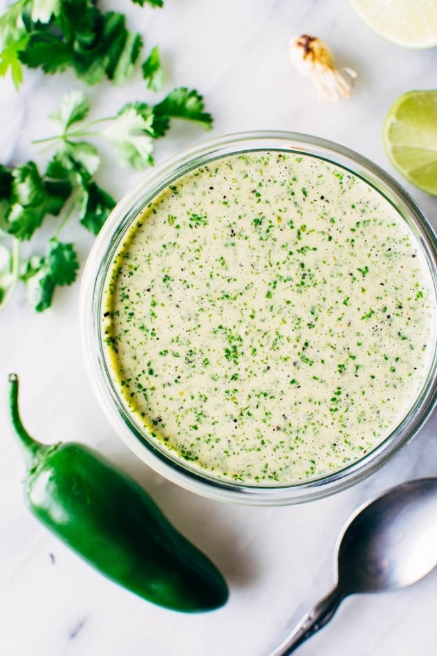 Green sauce for mango chorizo taco salad bowls! Spicy crumbled chorizo layered over salad greens with a rainbow of veggies and all your favorite toppings.