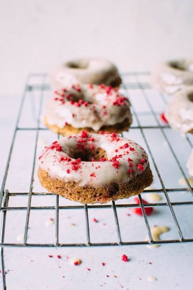 Grain free raspberry donuts with a vanilla coconut glaze! Crumbly in all the right ways, slightly springy in texture, studded with fresh raspberries, dipped in a luscious vanilla coconut glaze and sprinkled with tart dried raspberries.