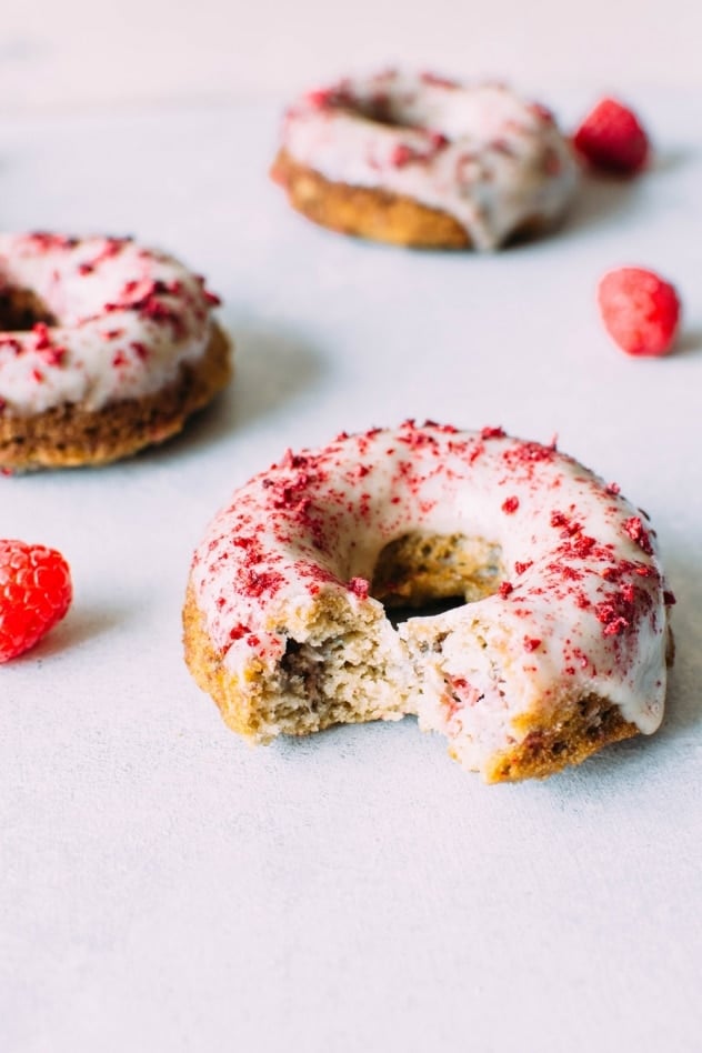 Grain free raspberry donuts with a vanilla coconut glaze! Crumbly in all the right ways, slightly springy in texture, studded with fresh raspberries, dipped in a luscious vanilla coconut glaze and sprinkled with tart dried raspberries.
