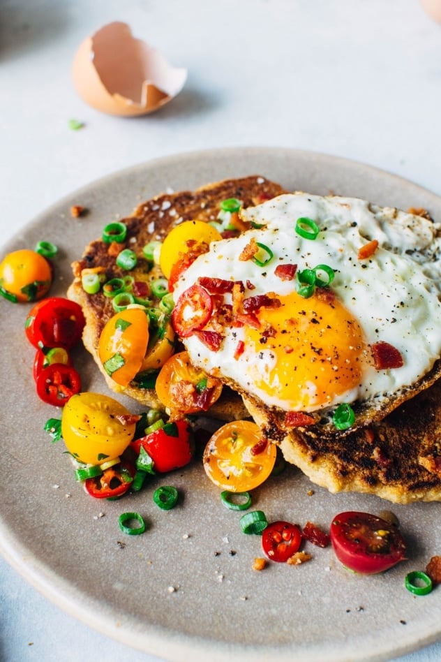 A crazy easy and delicious recipe for savory breakfast pancakes! Made with crumbled bacon, green onions, and topped with a tomato jalapeño salad and fried eggs, these pancakes are the perfect reason to stay home and cook breakfast this weekend! 