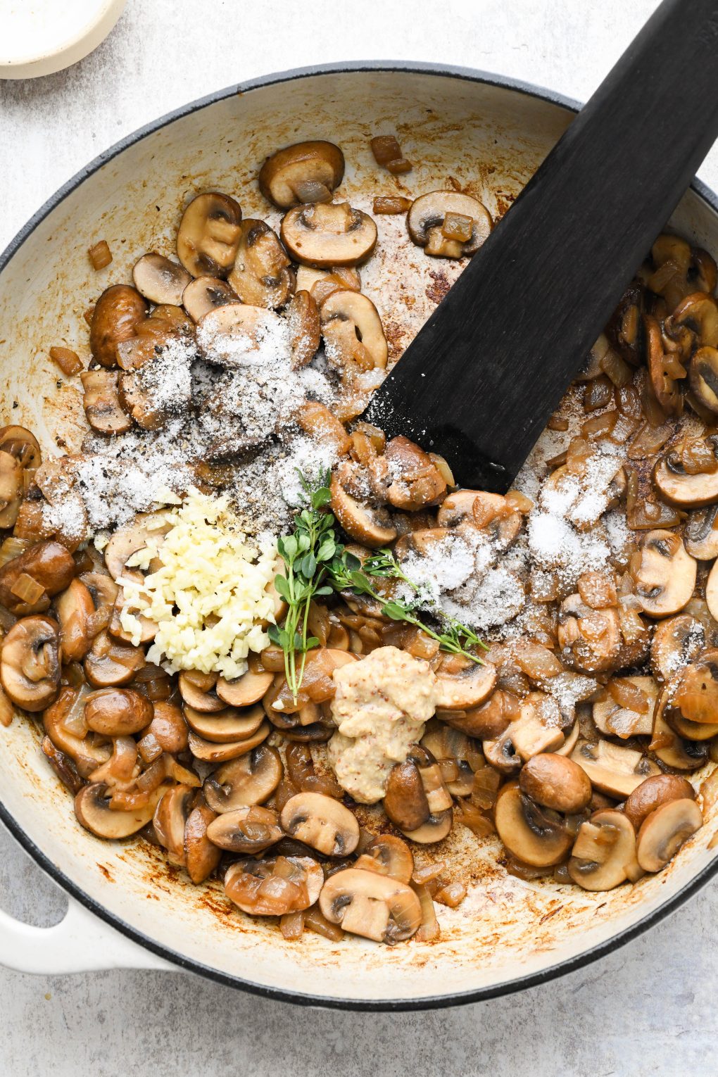 Sauteed mushrooms and onions in a large ceramic skillet with fresh thyme, garlic, salt, and pepper. 