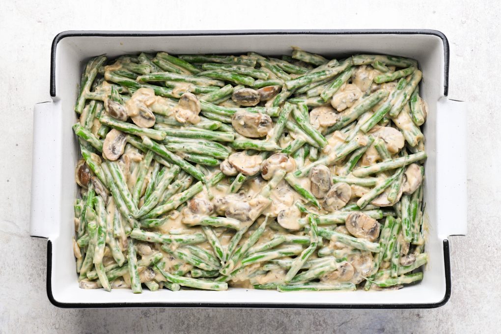 Green beans tossed with creamy mushroom sauce in a 9x13 baking dish.