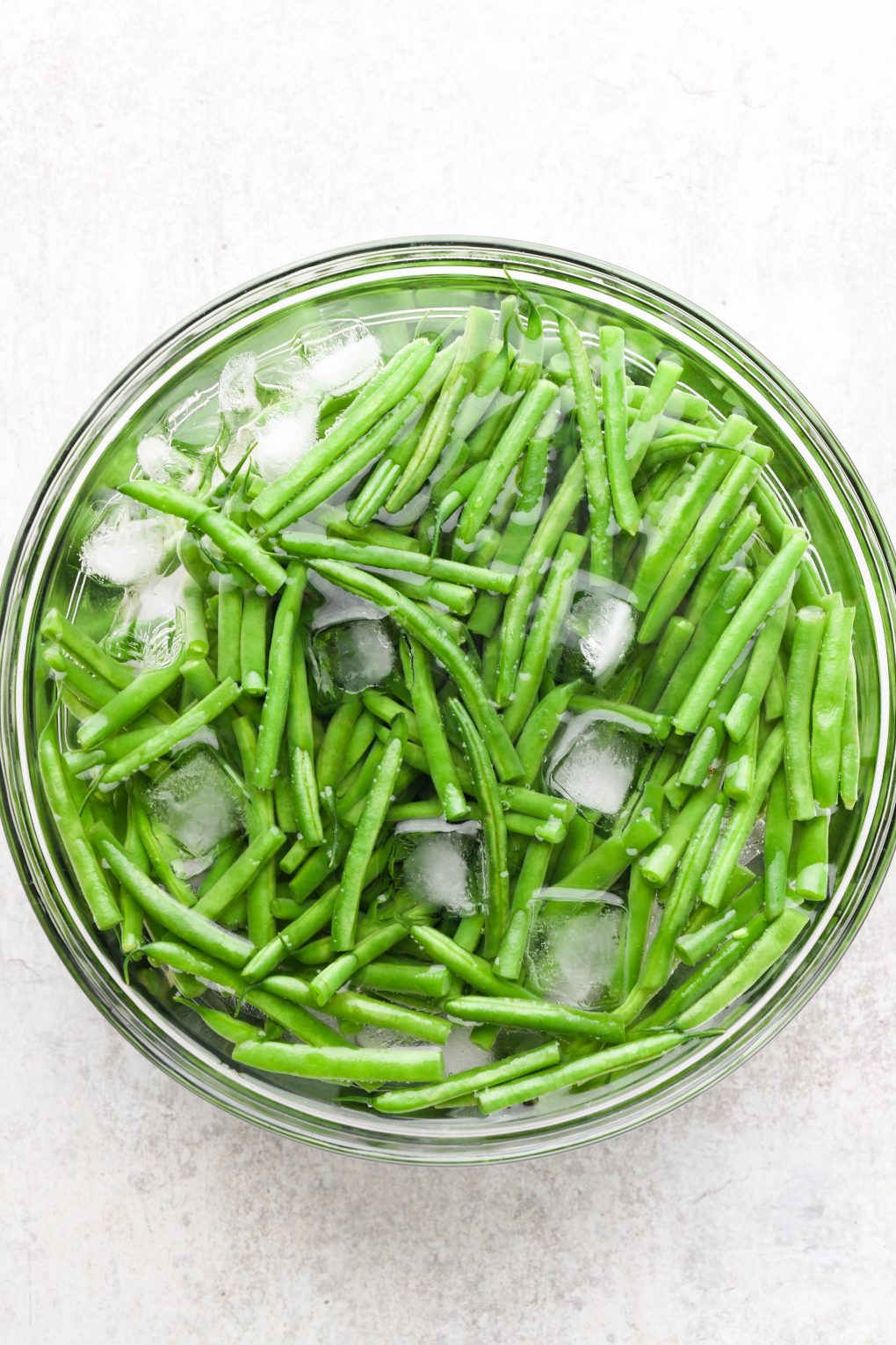 Blanched green beans in a bowl of ice water.