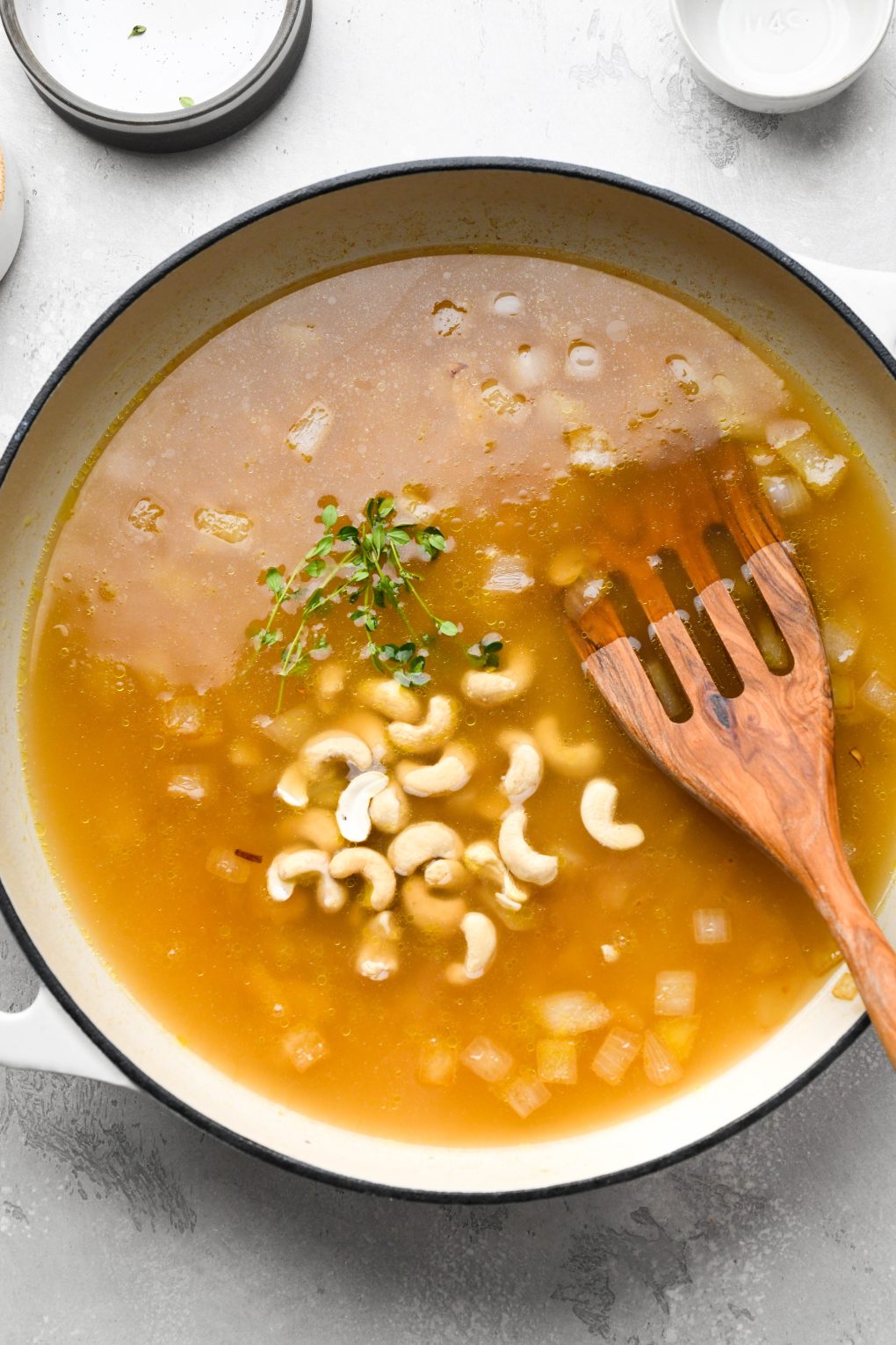 Photos showing how to make Whole30 gravy - broth poured into skillet with diced onions, raw cashews, and fresh thyme.