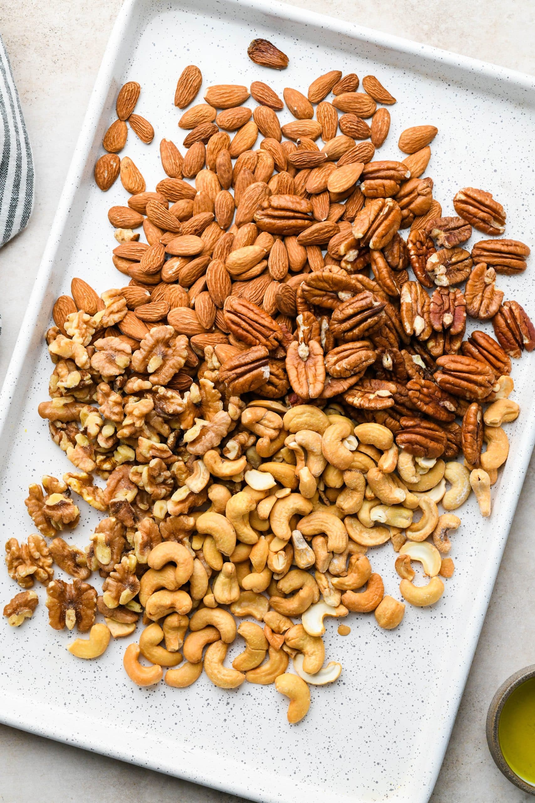 How to make Spiced Roasted Nuts: Mixed nuts spread out on a baking sheet.