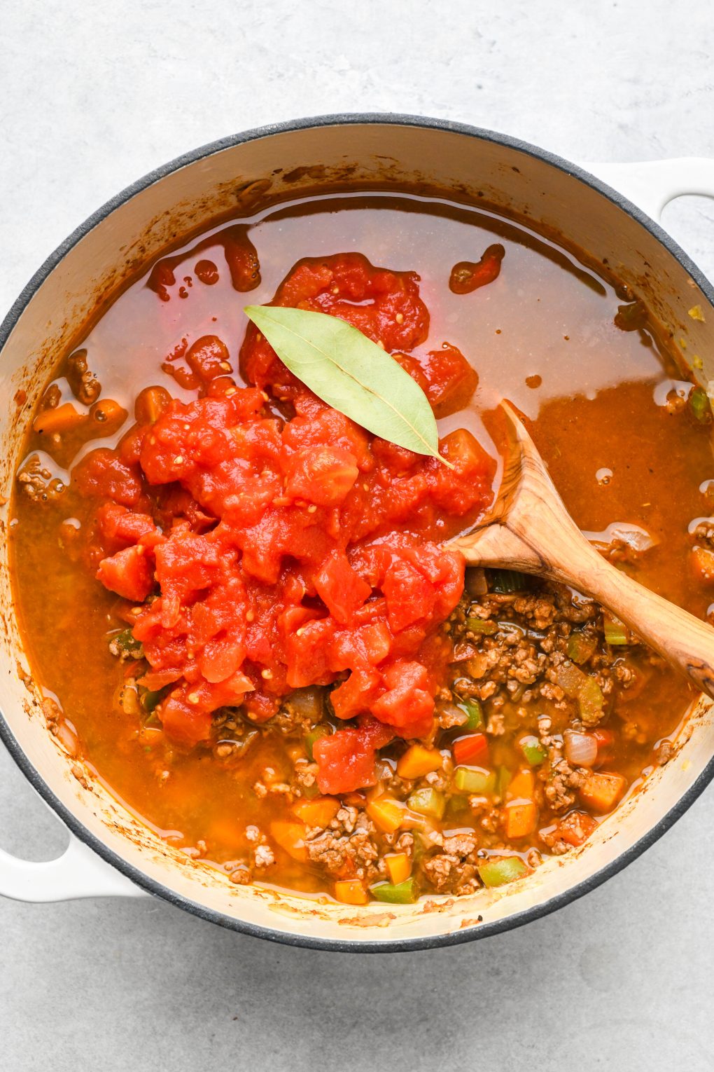 How to make beanless Whole30 chili: Broth, diced tomatoes, and bay leaf added to the large soup pot. 