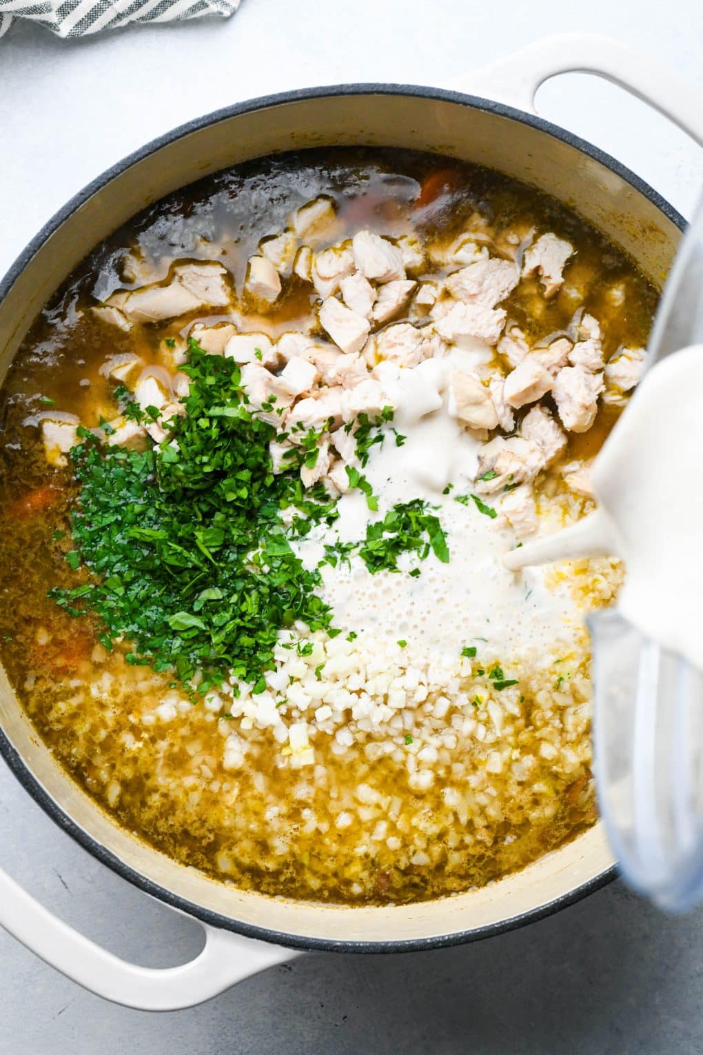 How to make Creamy Dairy Free Chicken and Cauliflower Rice Soup: Chicken added back to the soup along with cashew cream, cauliflower rice, and fresh herbs. 