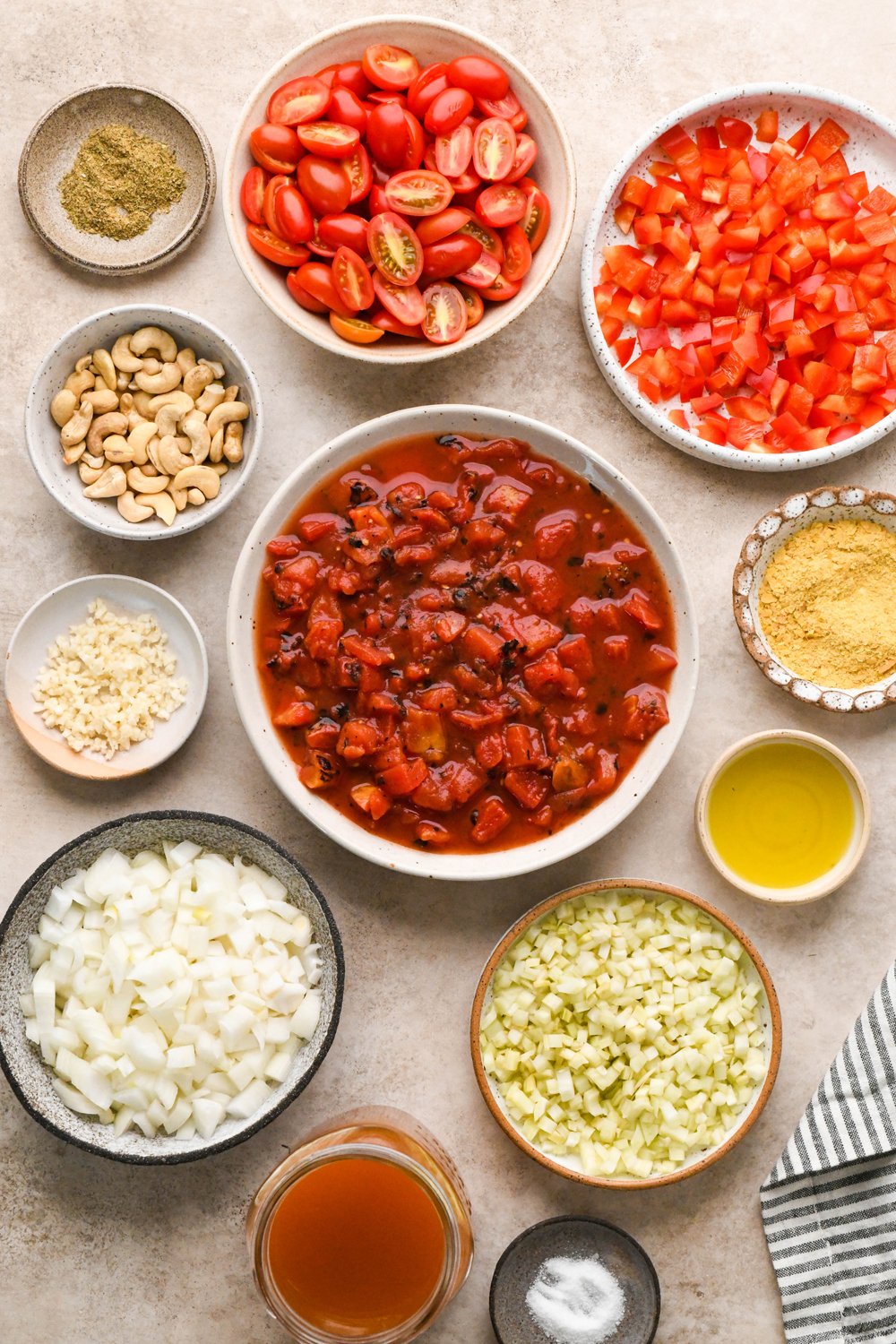 Ingredients for Dairy Free Tomato Red Pepper Soup in various ceramics on a light creamy brown background.