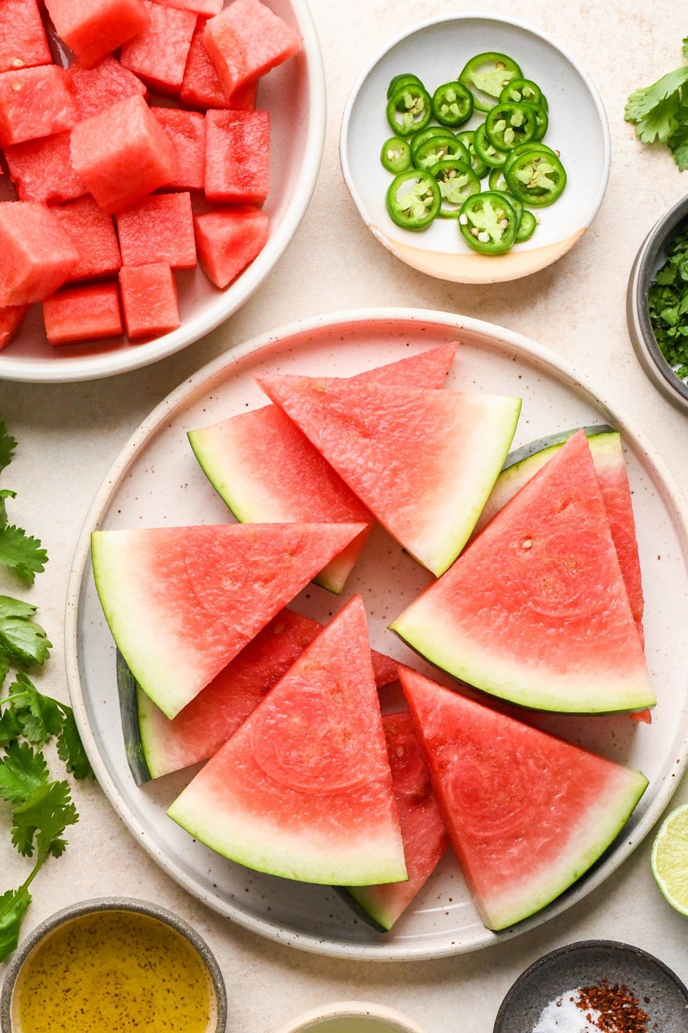 How to make spicy watermelon salad: Watermelon wedges on a plate and cubed watermelon in a shallow bowl.