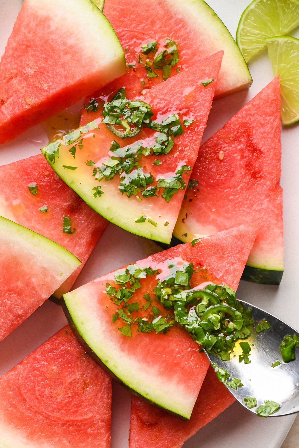 How to make spicy watermelon salad: Spooning the dressing over watermelon wedges on a large serving platter.