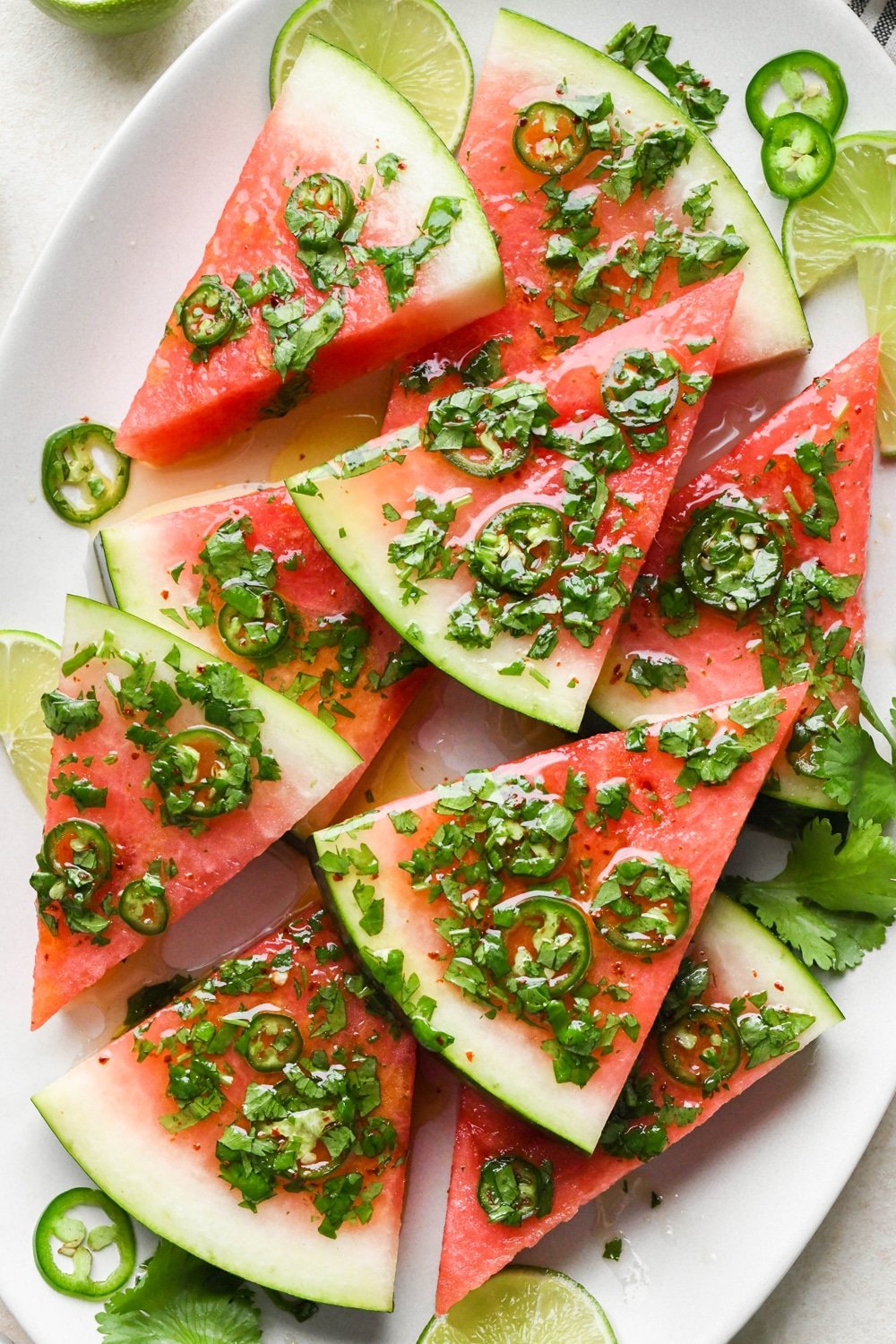Watermelon wedges piled on a serving platter and draped in a spicy lime and cilantro dressing.