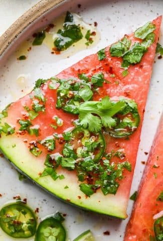 How to make spicy watermelon salad: Watermelon wedge with dressing on a ceramic plate.