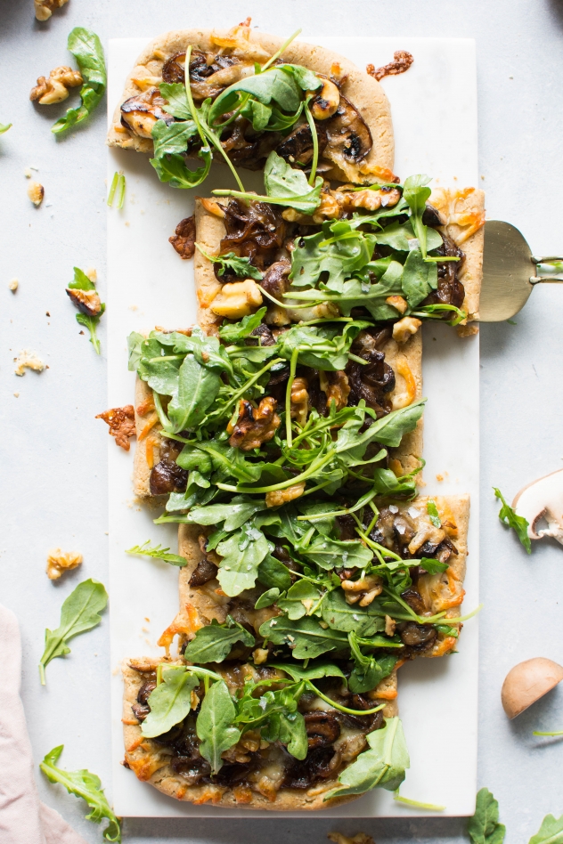 This grain free caramelized onion and mushroom pizza with arugula is made with Simple Mills almond flour pizza dough, topped with flavorful caramelized onions and mushrooms, smoked mozzarella cheese, and a peppery + bright arugula and toasted walnut salad - basically making it the ideal healthy pizza situation! 