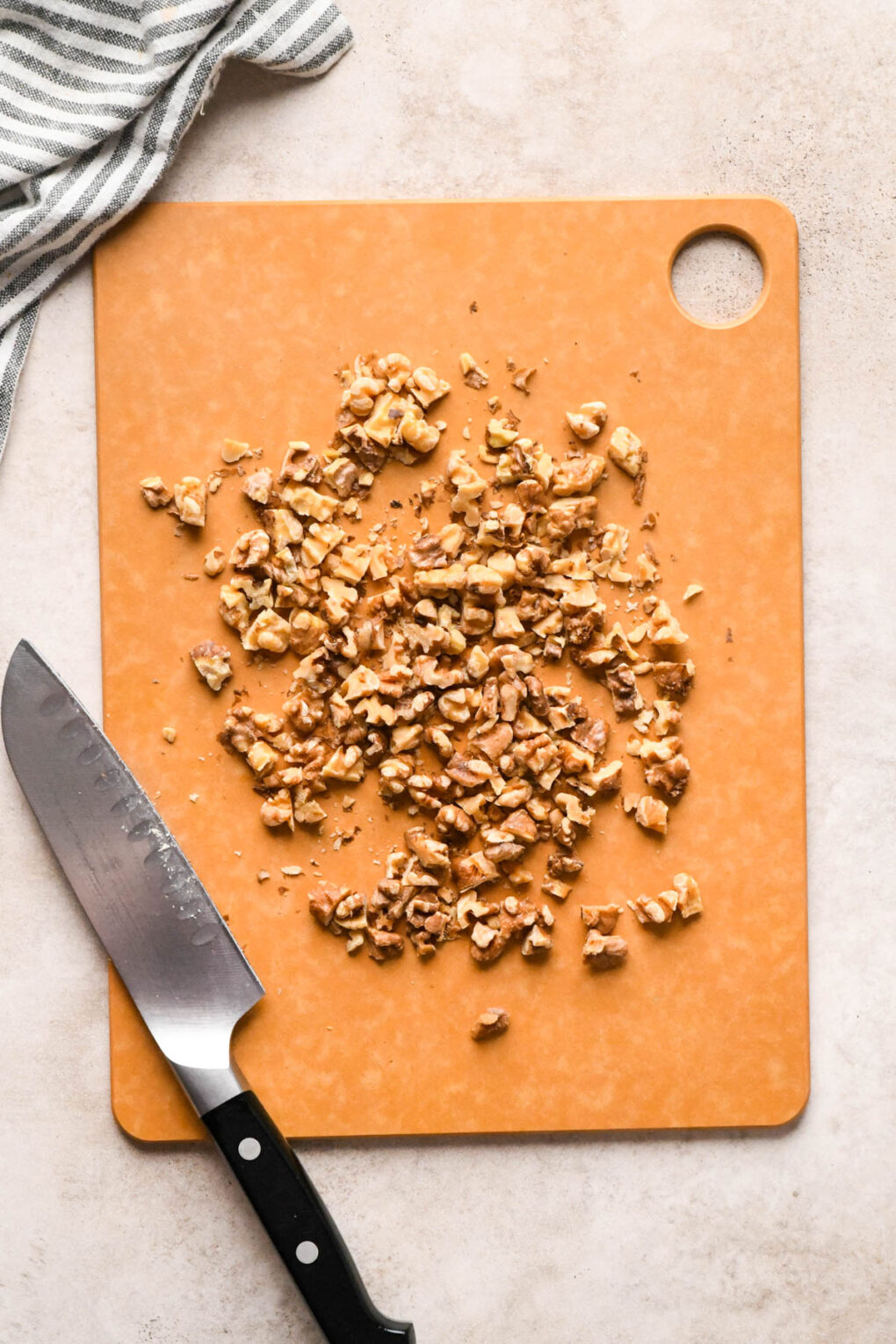 How to make Asian Pear and Walnut Salad with Maple Mustard Dressing: Walnuts on a cutting board, after roughly chopping with a knife.