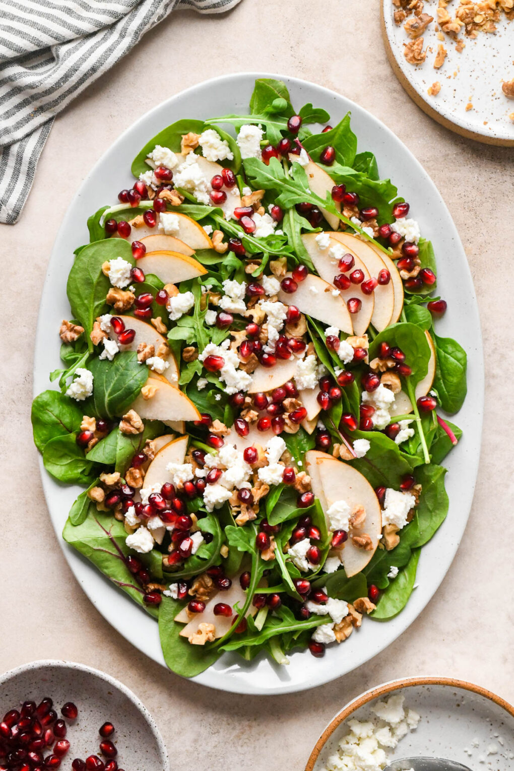How to make Asian Pear and Walnut Salad with Maple Mustard Dressing: Pomegranate, chopped walnuts, and feta cheese added to the salad serving platter.