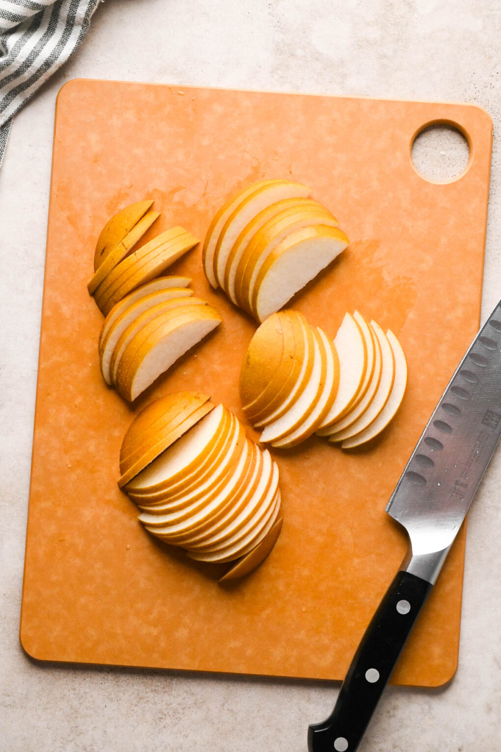How to make Asian Pear and Walnut Salad with Maple Mustard Dressing: Thinly sliced asian pears on a cutting board.