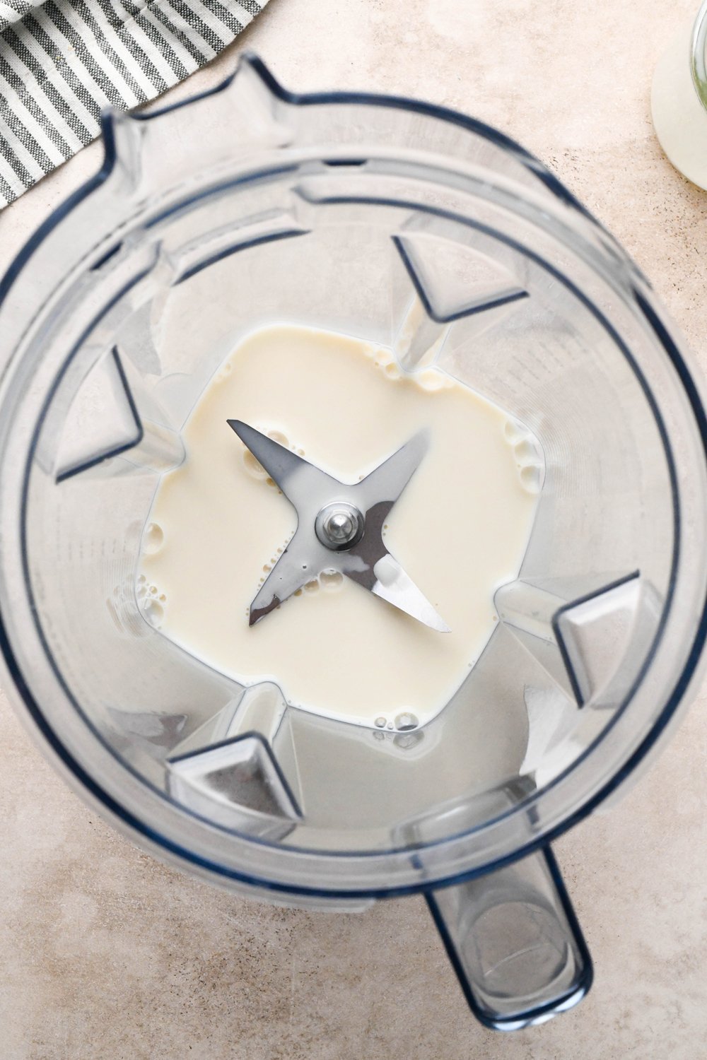 Step-by-step for how to make Raspberry Mango Smoothie with Greek Yogurt: Dairy free milk in blender container.