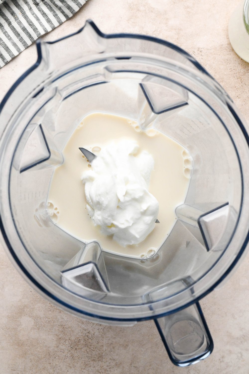 Step-by-step for how to make Raspberry Mango Smoothie with Greek Yogurt: Dairy free milk and yogurt in blender container.