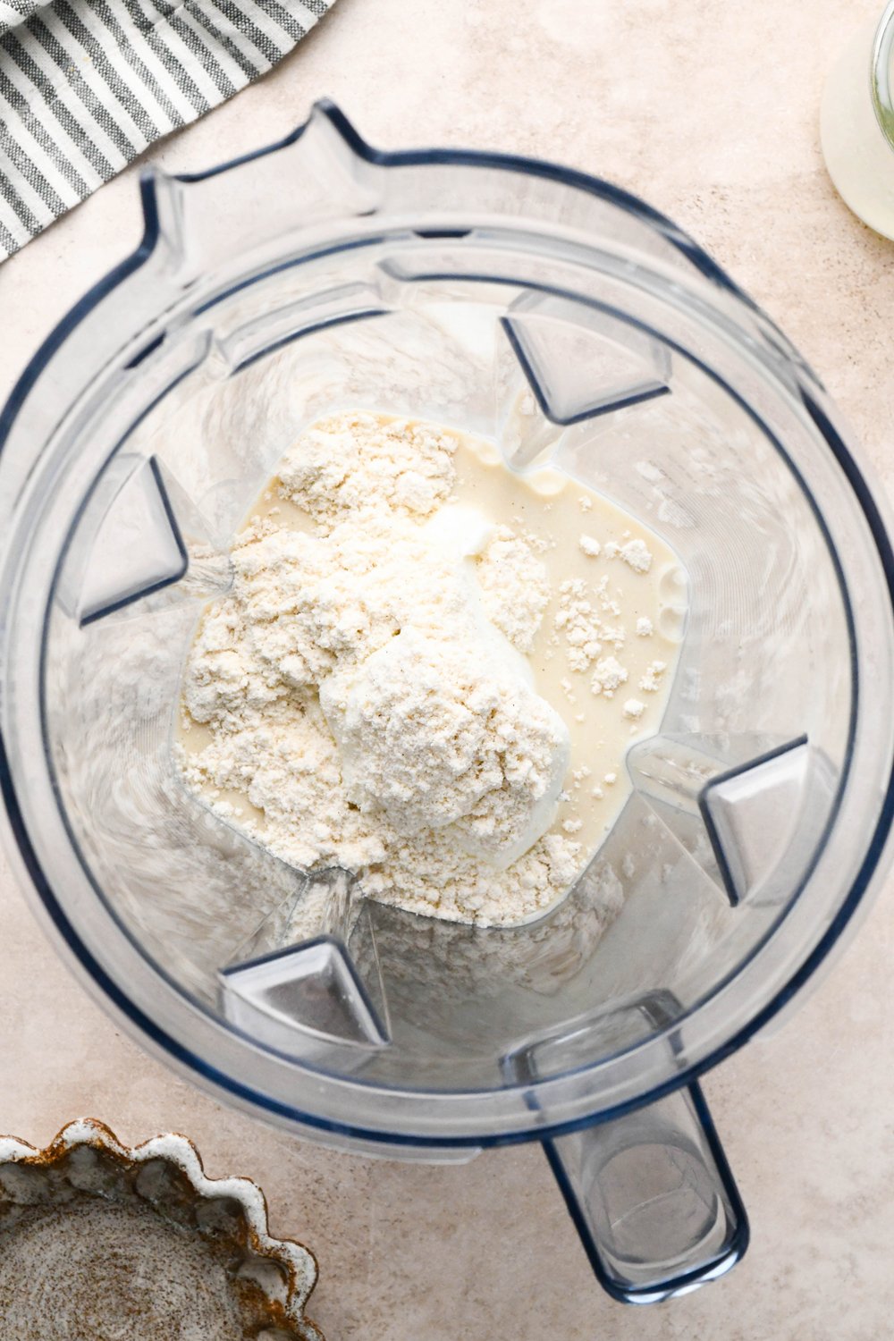 Step-by-step for how to make Raspberry Mango Smoothie with Greek Yogurt: Dairy free milk, yogurt, and protein powder in blender container.