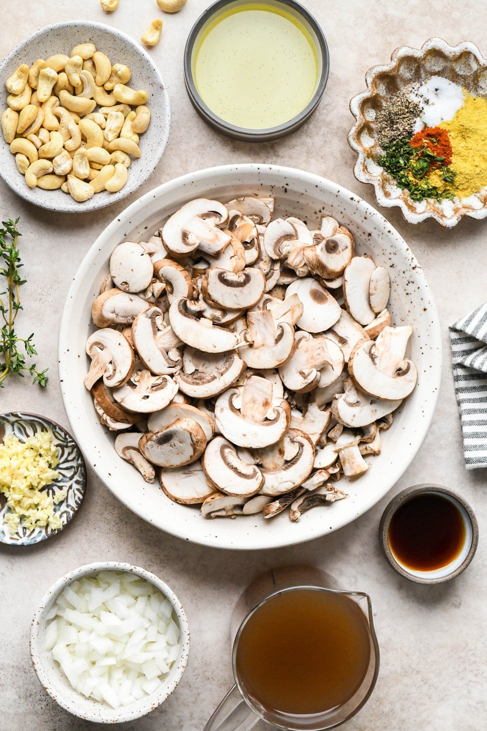 Gluten free mushroom gravy ingredients in various ceramics on a light brown background.