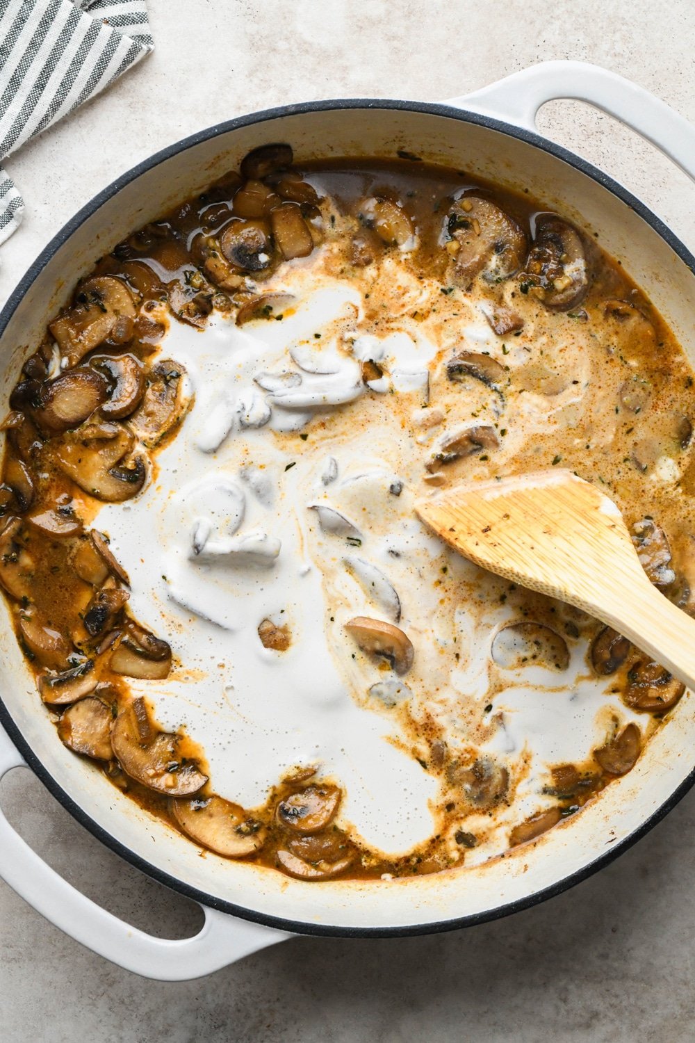 How to make Gluten Free Mushroom Gravy: Stirring cashew cream into skillet with mushrooms and broth.