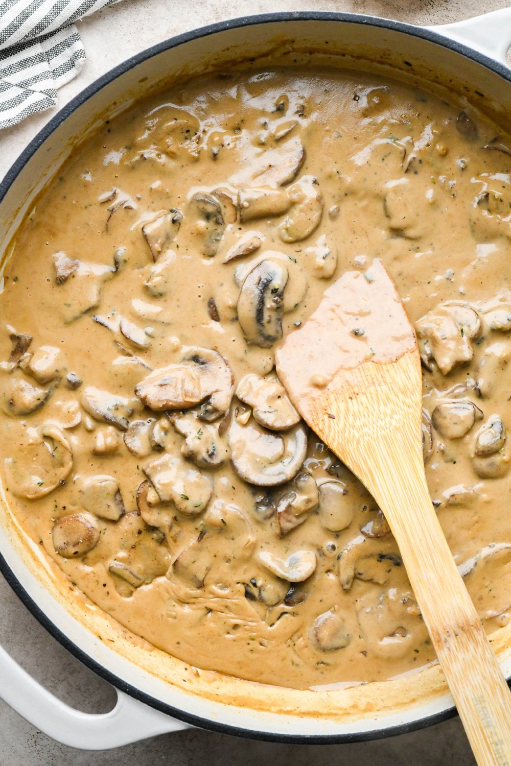 How to make Gluten Free Mushroom Gravy: Close up of finished mushroom gravy in large skillet with sliced mushrooms and creamy gravy base.