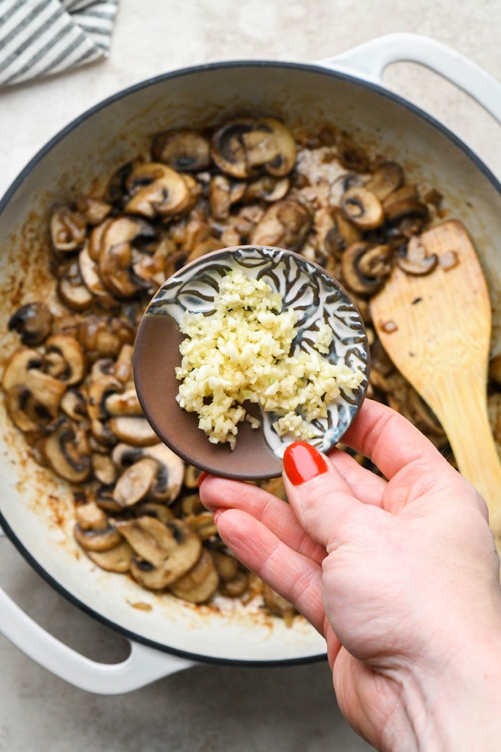 How to make Gluten Free Mushroom Gravy: Adding chopped garlic to skillet with sautéed mushrooms.