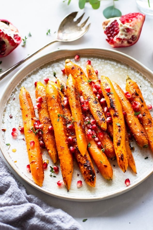These maple chili glazed carrots with thyme and pomegranate are an easy and delicious side dish for your holiday table. Paleo, vegan and oh-so-yummy! Savory and sweet - loaded up with fresh and bright pomegranate seeds to delight your taste buds!