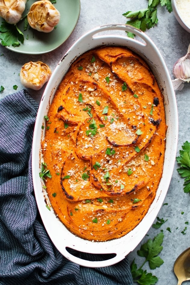 This twice baked garlic parmesan sweet potato casserole is a savory twist on a classic autumn side dish. Made with smooth and luscious sweet potatoes, parmesan cheese, and roasted garlic. Nourishing, delicious, and full of flavor! 