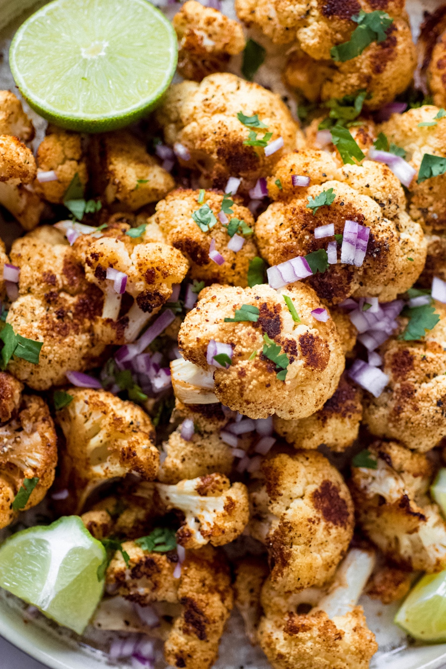 Close up of mexican roasted cauliflower, topped with chopped red onion and cilantro.