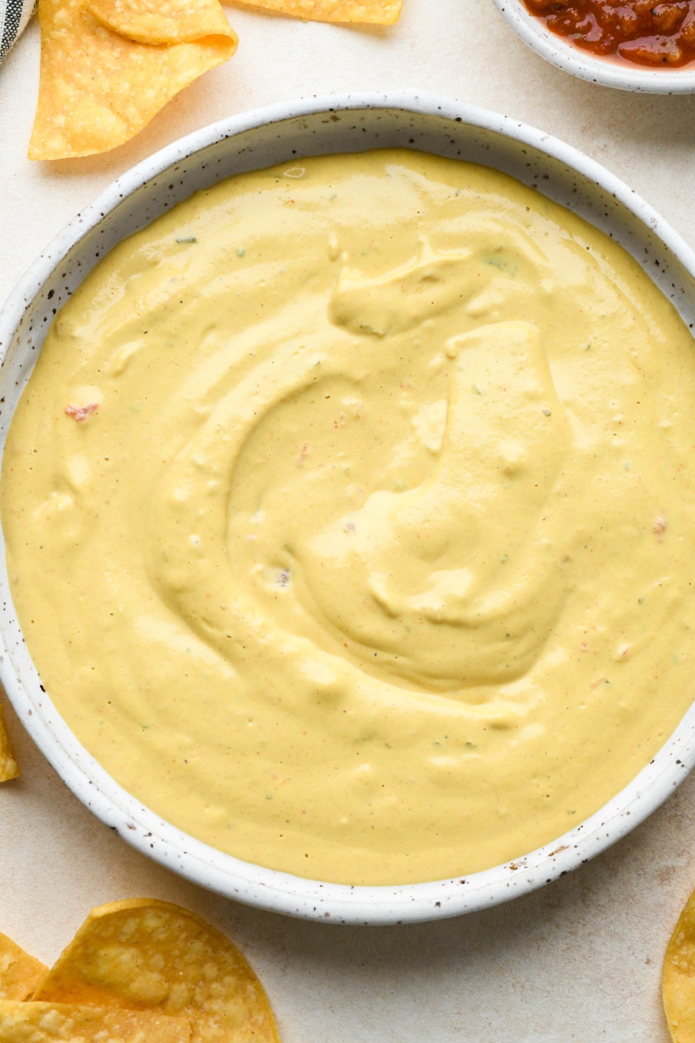 How to make cashew queso: Cashew queso in a shallow ceramic bowl with salsa, after stirring to combine.