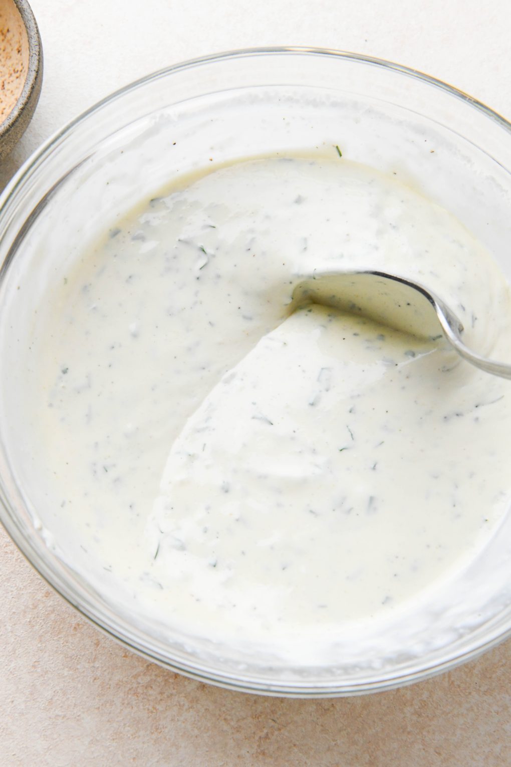 How to make dairy free ranch dressing: A spoon dipping into the bowl of ranch dressing to show consistency.