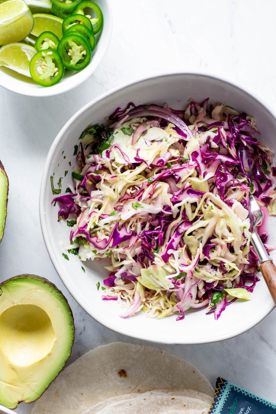 Close up of a bowl of cabbage and red onion slaw for mexican roasted cauliflower tacos